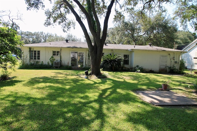 rear view of house with central AC and a yard