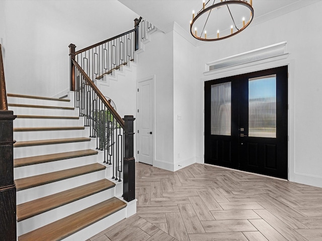 entryway featuring a chandelier, french doors, crown molding, and light parquet floors