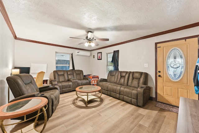 living room featuring ceiling fan, an AC wall unit, a wealth of natural light, light hardwood / wood-style flooring, and a textured ceiling