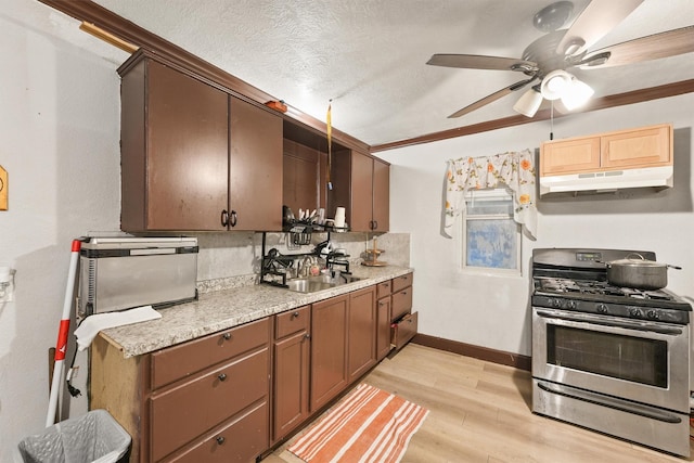 kitchen featuring light hardwood / wood-style floors, gas stove, tasteful backsplash, a textured ceiling, and sink