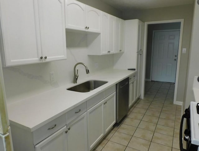 kitchen featuring stainless steel dishwasher, light tile patterned floors, sink, and white cabinetry