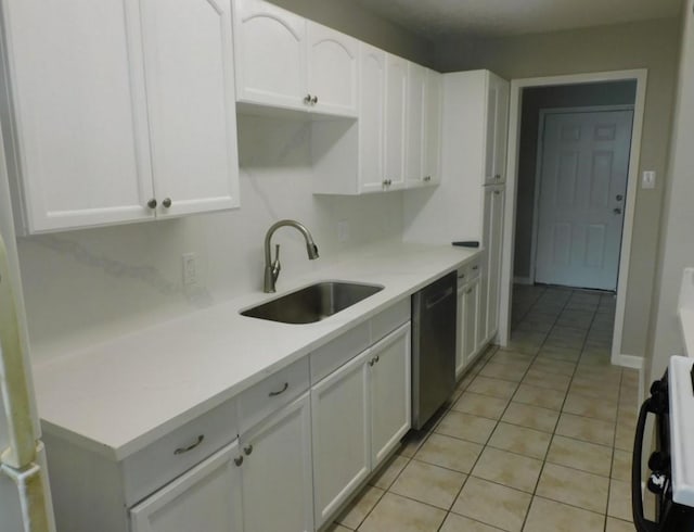 kitchen with stainless steel dishwasher, stove, light tile patterned flooring, sink, and white cabinets