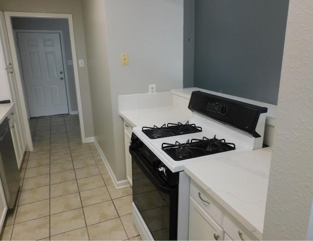 kitchen featuring range with gas stovetop, white cabinetry, black dishwasher, light stone counters, and light tile patterned floors