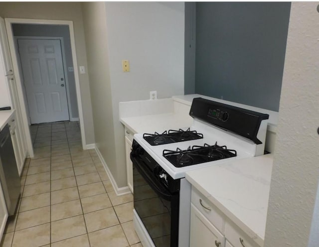 kitchen featuring light tile patterned floors, white cabinets, range with gas cooktop, and light stone countertops