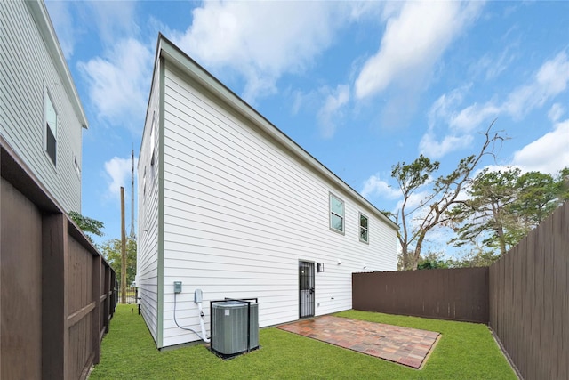 back of house featuring central AC, a lawn, and a patio