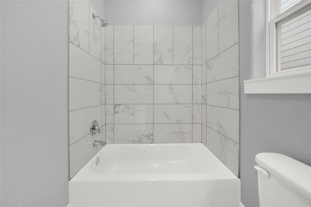 bathroom with toilet and tiled shower / bath