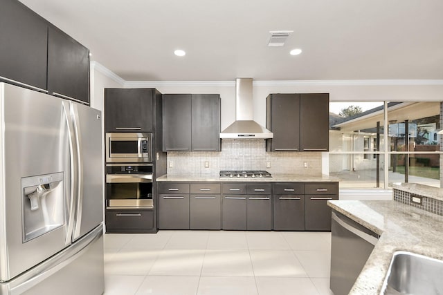 kitchen with appliances with stainless steel finishes, wall chimney exhaust hood, tasteful backsplash, light tile patterned flooring, and light stone counters