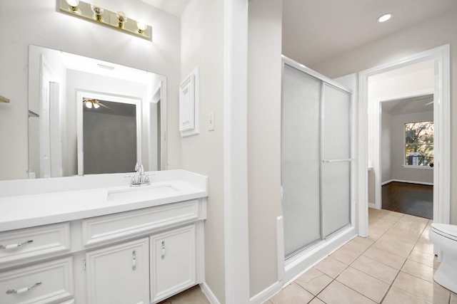 bathroom with toilet, a shower with shower door, ceiling fan, tile patterned floors, and vanity