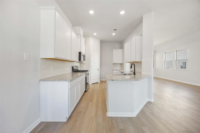 kitchen with stainless steel appliances, backsplash, white cabinetry, and sink