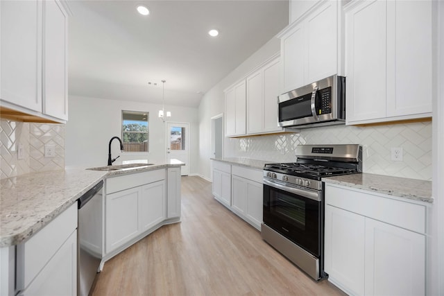 kitchen featuring pendant lighting, sink, white cabinetry, appliances with stainless steel finishes, and light stone counters