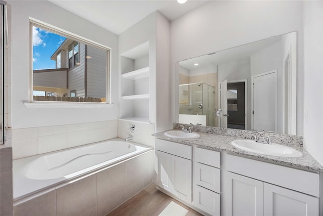 bathroom with independent shower and bath, built in features, wood-type flooring, and vanity