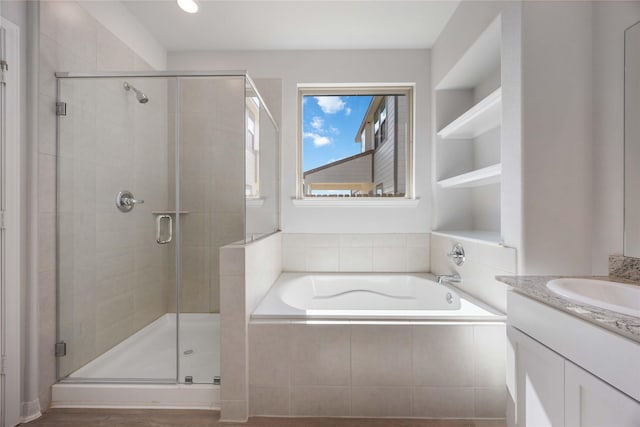 bathroom featuring built in shelves, vanity, and separate shower and tub