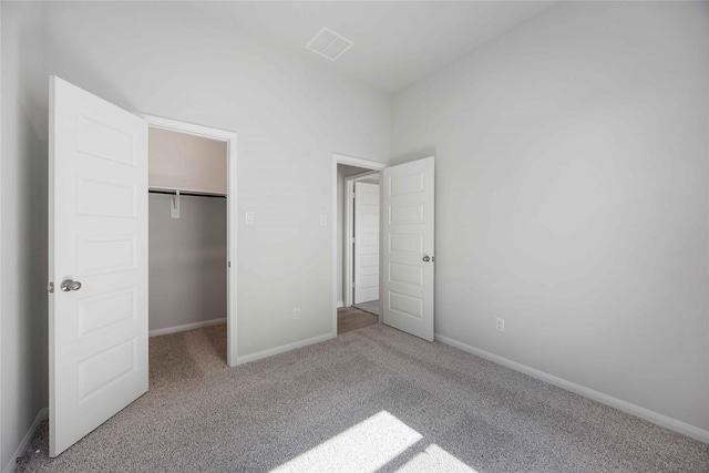 unfurnished bedroom featuring a spacious closet, a closet, and light colored carpet