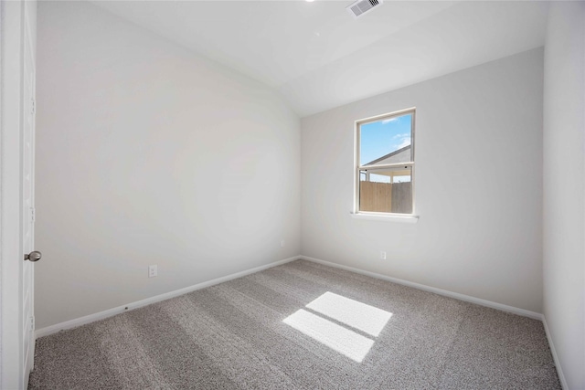 carpeted spare room with vaulted ceiling