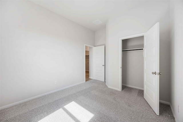 unfurnished bedroom with light colored carpet and a closet