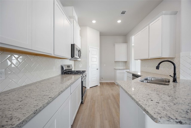 kitchen featuring light hardwood / wood-style floors, sink, white cabinetry, light stone countertops, and stainless steel appliances