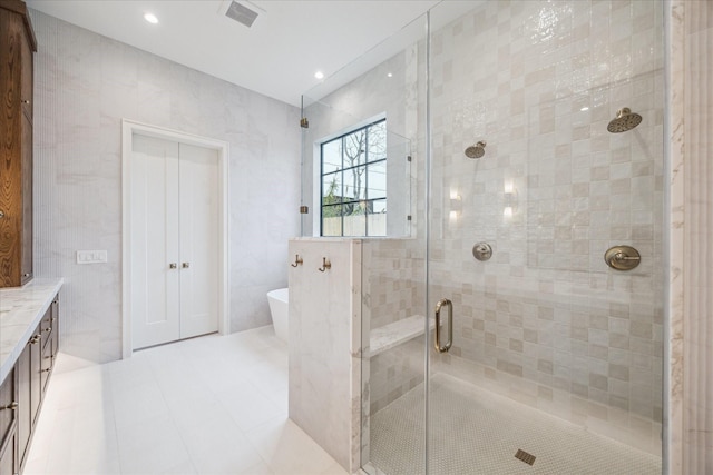 bathroom with shower with separate bathtub, tile walls, and vanity