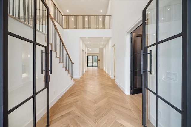 entryway with french doors, light parquet floors, and a high ceiling