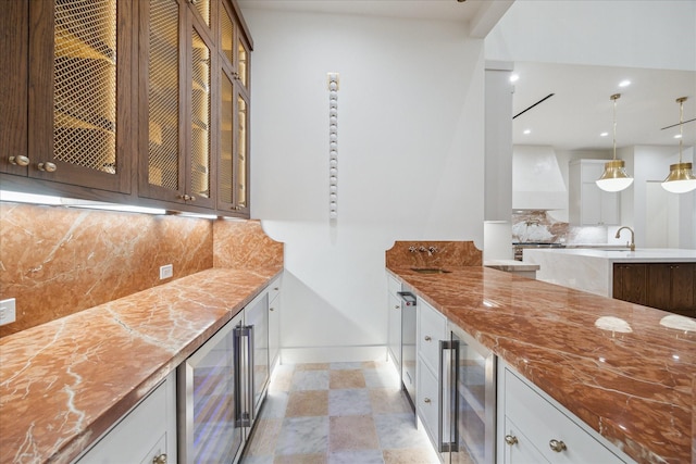 kitchen with wine cooler, decorative light fixtures, custom range hood, decorative backsplash, and white cabinets