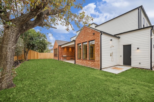 rear view of property featuring a yard and a patio area