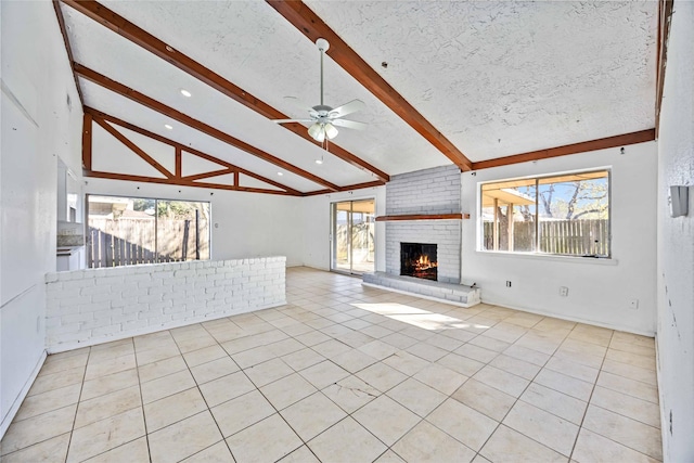 unfurnished living room with a fireplace, lofted ceiling with beams, ceiling fan, and a healthy amount of sunlight