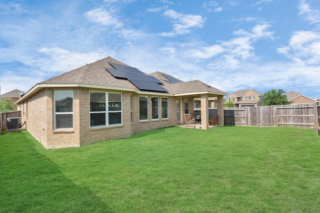 back of property with a patio area, a lawn, and solar panels