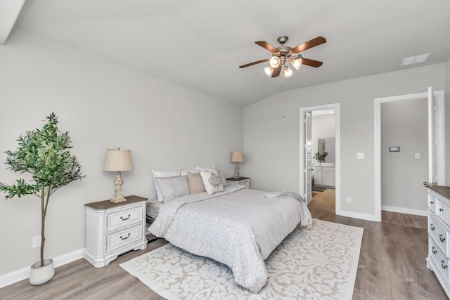 bedroom featuring ceiling fan, light hardwood / wood-style floors, connected bathroom, and vaulted ceiling