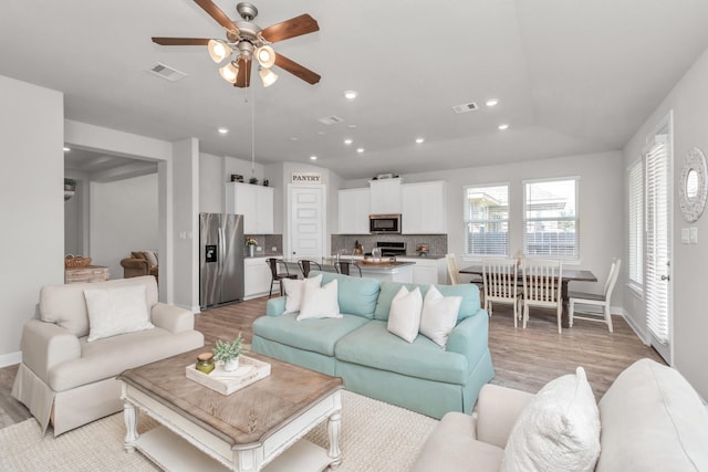 living room featuring ceiling fan, lofted ceiling, and light wood-type flooring