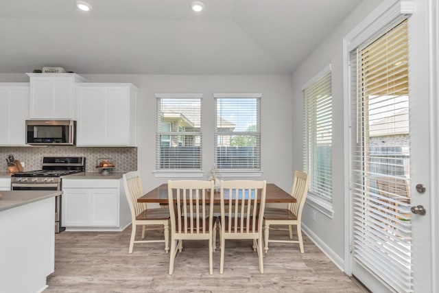 dining area featuring light wood-type flooring and vaulted ceiling