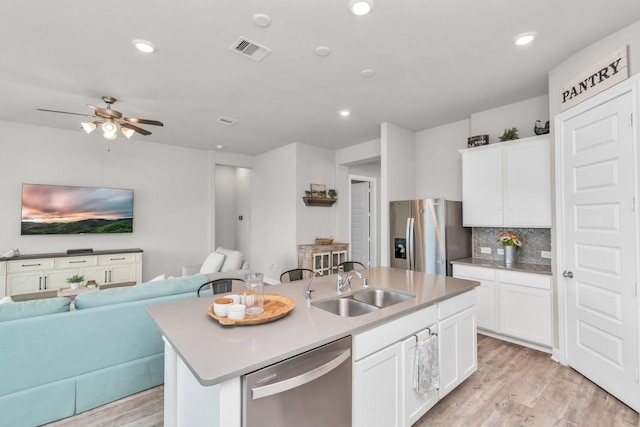 kitchen featuring decorative backsplash, sink, an island with sink, stainless steel appliances, and white cabinets