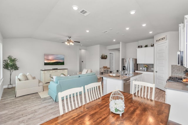 dining area featuring vaulted ceiling, ceiling fan, light hardwood / wood-style flooring, and sink