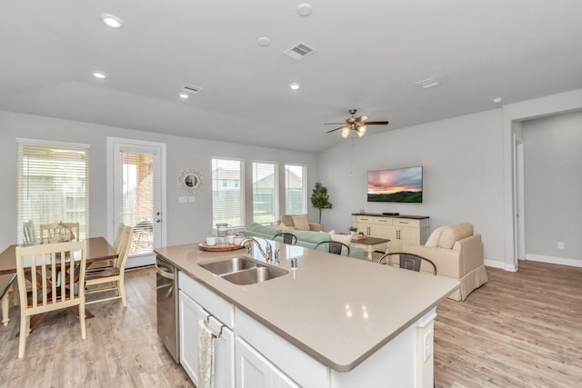 kitchen with sink, white cabinets, lofted ceiling, and an island with sink