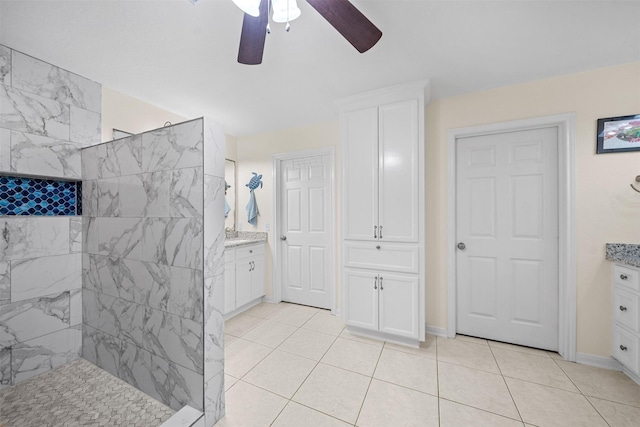 bathroom with ceiling fan, vanity, a tile shower, and tile patterned flooring