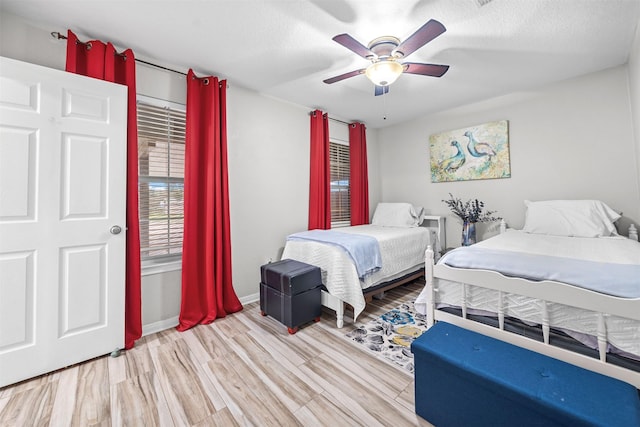 bedroom with light wood-type flooring, ceiling fan, and a textured ceiling