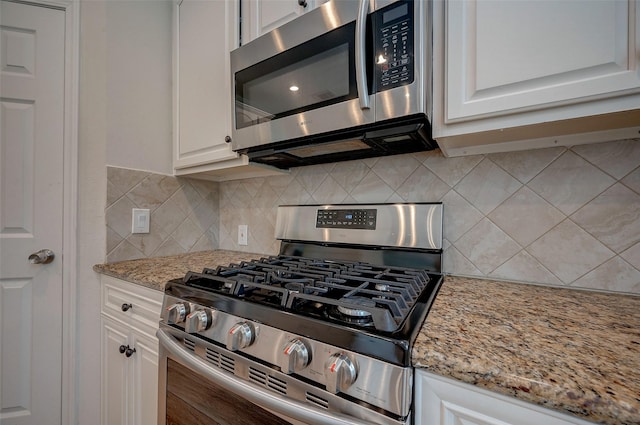 kitchen with light stone countertops, decorative backsplash, appliances with stainless steel finishes, and white cabinetry