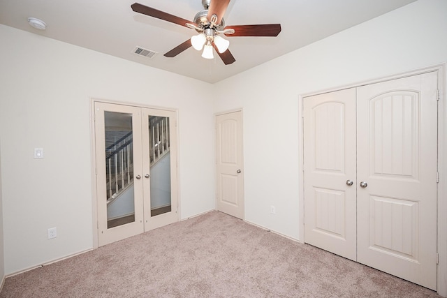 unfurnished bedroom featuring ceiling fan, access to exterior, light carpet, and french doors