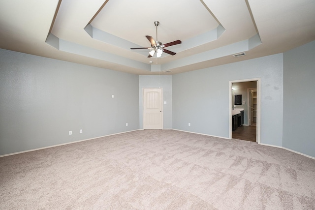 carpeted spare room featuring ceiling fan and a tray ceiling