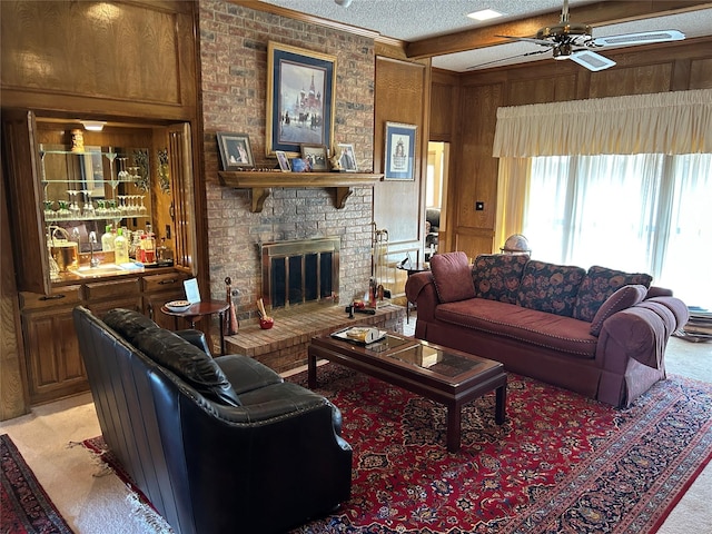 living room with ceiling fan, a brick fireplace, wood walls, beam ceiling, and light carpet