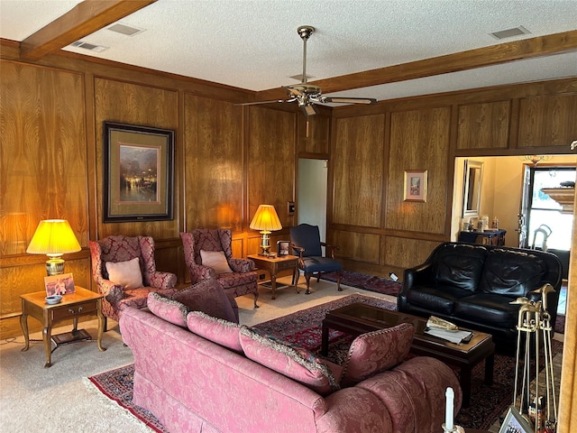 living room with wooden walls, ceiling fan, light colored carpet, a textured ceiling, and beam ceiling