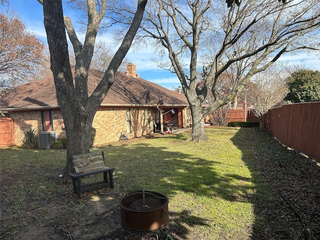 view of yard with central AC and a fire pit