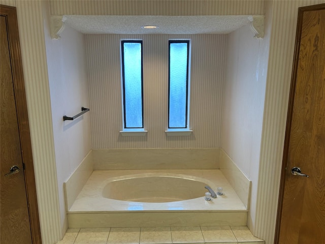 bathroom with a textured ceiling, a tub to relax in, and tile patterned flooring