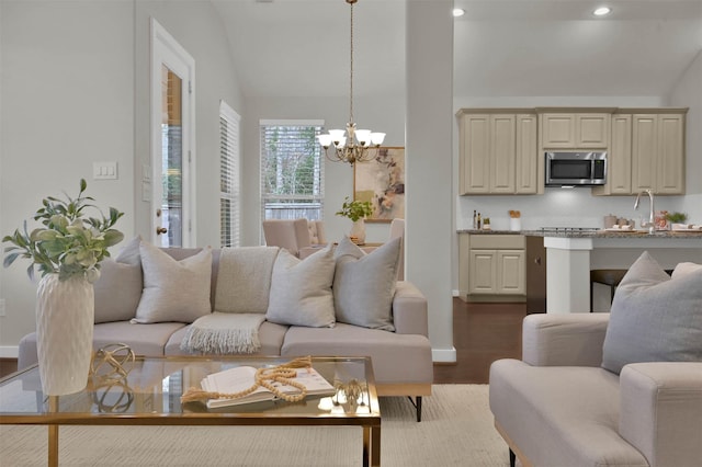 living room with sink, hardwood / wood-style flooring, vaulted ceiling, and a chandelier