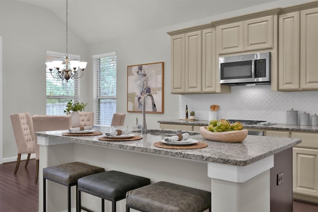 kitchen with lofted ceiling, sink, a notable chandelier, cream cabinets, and a center island with sink