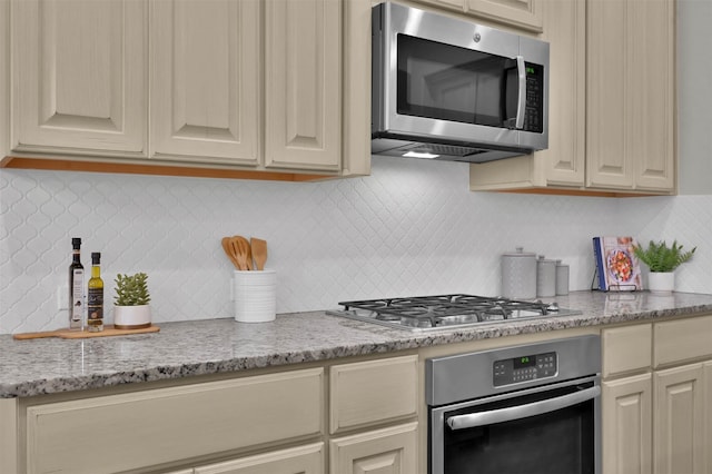 kitchen with light stone countertops, decorative backsplash, and stainless steel appliances