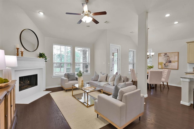 living room featuring lofted ceiling, dark wood-type flooring, and ceiling fan with notable chandelier