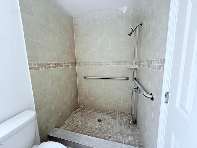 bathroom featuring toilet and a tile shower