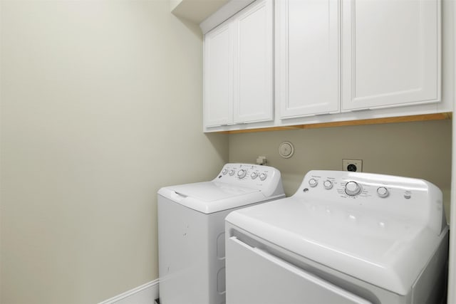 clothes washing area with cabinets and separate washer and dryer