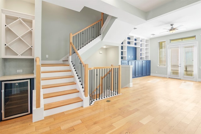 stairs featuring ceiling fan, built in features, french doors, beverage cooler, and wood-type flooring