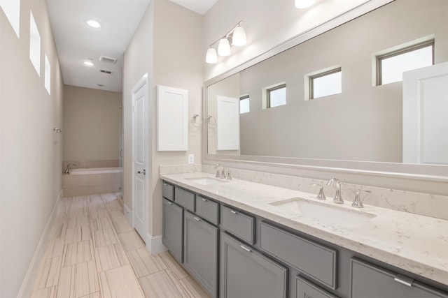 bathroom featuring a relaxing tiled tub and vanity