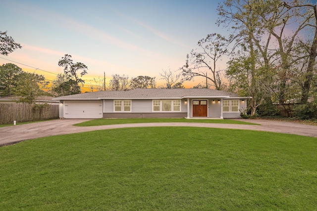 ranch-style home featuring a garage and a lawn